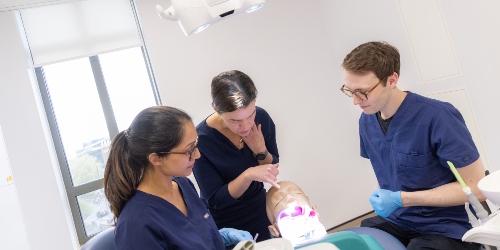 A periodontology class with staff, students and phantom head on clinic